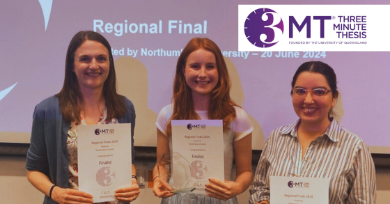 Three students standing presenting their certificates for the Three Minute Thesis, the person in the middle is Jo Baker, who is holding glass award