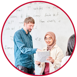 Colleague and student looking at paper in front of whiteboard