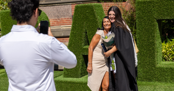 Person taking photo of graduate and family member