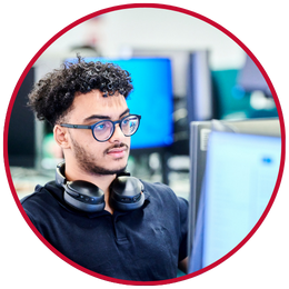 Student working at computer with headphones round neck