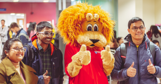 Students smiling with thumb up next to Percy the Lion