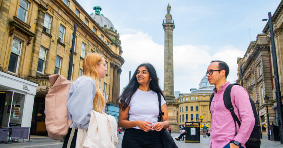 Students stood chatting with Grey's Monument in the background