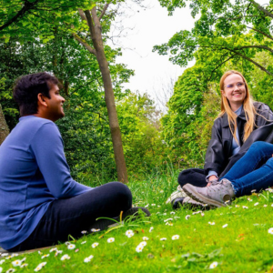 Two students sat on grass chatting