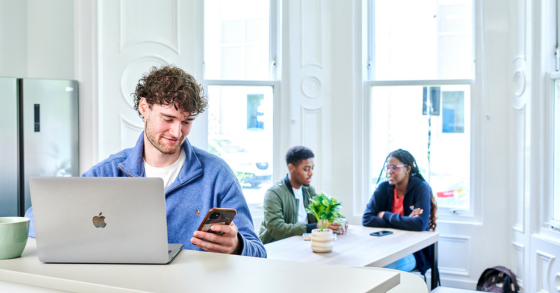 Student working in their living room, checking their phone