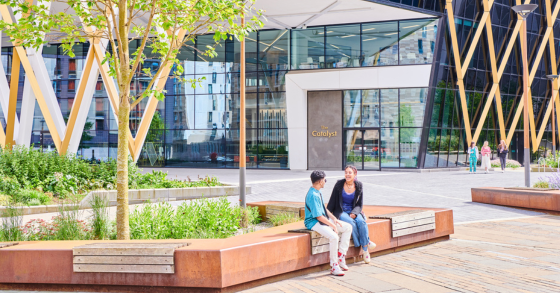 Two students sat in the sunshine outside the Catalyst building