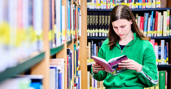 Student in the Library reading a textbook 