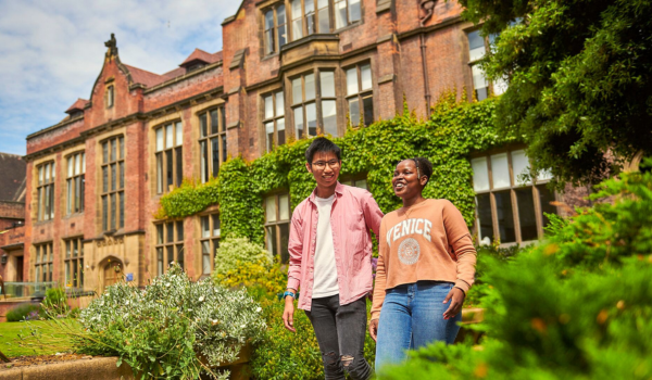 Two students walking and talking through a university garden