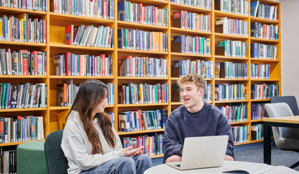 two students working on campus with books