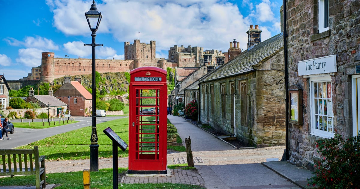 Cottages leading up to Bamburgh Castle, with a red phone box in the foreground.