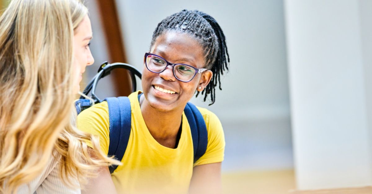 Female student smiles at another student in university hall 